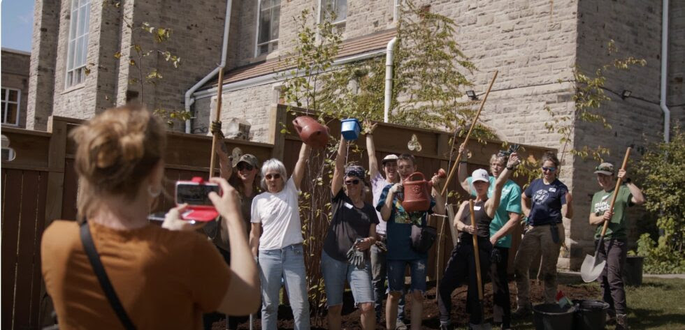 a group of people celebrating planting trees and other plants. 