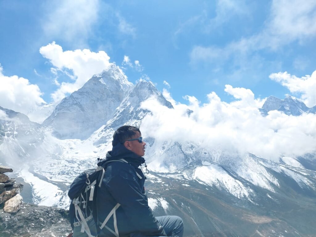 Man sitting in front of a mountain covered in snow