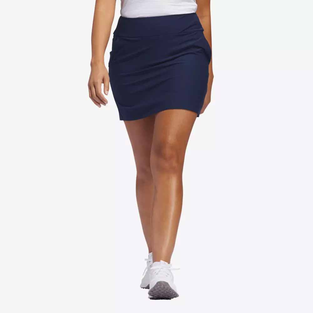 A person wearing a white top, navy blue athletic skirt, and white sneakers is walking forward against a plain light background&mdash;perfect apparel for stepping out in style this Mother&rsquo;s Day.