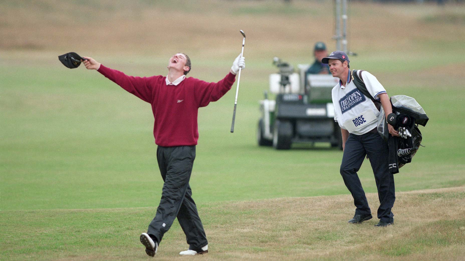 A golfer in a red sweater celebrates with arms raised and mouth open, holding a cap and club, echoing Justin Rose&rsquo;s iconic moments, while a smiling caddie stands nearby on a golf course with green and brown grass.