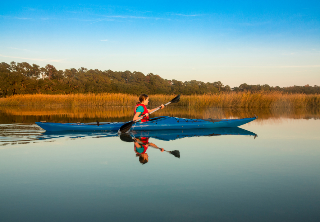 Teen kayaking through glassy water