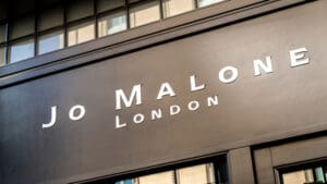 British perfumier Jo Malone is being sued by Estée Lauder Companies for using her own name in a fragrance collaboration with high street retailer Zara, in a legal dispute that highlights the complexities of brand ownership when a founder sells the rights to their name. The American cosmetics giant purchased Malone’s original fragrance business, Jo Malone London, in 1999, acquiring not only the brand but also the commercial rights associated with her name. The deal allowed Estée Lauder to expand the luxury fragrance label globally, but it also placed contractual restrictions on Malone’s ability to use the “Jo Malone” name in connection with fragrance marketing in the future. The latest dispute relates to a collaboration between Zara and Malone’s newer brand, Jo Loves. The partnership, which began in 2019, produced a range of fragrances sold through Zara stores and online platforms. However, Estée Lauder has taken issue with the use of Malone’s name on the product packaging, which reportedly included the wording: “A creation by Jo Malone CBE, founder of Jo Loves.” Estée Lauder claims the wording breaches the terms agreed when Malone sold her original company. The group has filed legal action against Malone personally, her Jo Loves business and Zara’s UK arm, alleging trademark infringement, breach of contract and “passing off” — a legal claim that customers may be misled into believing the products are linked to the Jo Malone London brand. A spokesperson for Estée Lauder Companies said Malone had accepted clear contractual obligations when she sold the company more than two decades ago. The spokesperson said she had been compensated as part of the agreement and had complied with its terms for many years. They added that while Malone is free to pursue new business ventures, the company would act to protect the brand it had invested in building if contractual terms were breached. Zara UK has declined to comment on the case, and Malone has yet to publicly respond to the claims. Malone originally founded her fragrance business in the early 1990s, developing a reputation for distinctive scents inspired by British nature, gardens and seasonal ingredients. The brand quickly gained popularity for its elegant fragrances and minimalist design, expanding into candles, bath products and home fragrances before its acquisition by Estée Lauder. Following the sale, the brand grew into a global luxury fragrance powerhouse with boutiques around the world. However, Malone eventually stepped away from the company she founded. In 2011 she returned to the fragrance industry by launching Jo Loves, a new brand designed to reflect her continued passion for scent creation. The business focuses on niche fragrances and lifestyle products and operates independently of Jo Malone London. Despite this separation, the current lawsuit suggests Estée Lauder believes the Zara collaboration blurred the distinction between the two brands by prominently referencing Malone’s name in connection with fragrance products. The collaboration with Zara brought Malone’s fragrance expertise to a broader audience, with perfumes priced significantly lower than traditional luxury fragrances. Zara has increasingly developed partnerships with well-known perfumers as it expands its lifestyle and beauty offerings. However, the presence of Malone’s name on the packaging appears to have triggered legal concerns for Estée Lauder, which remains highly protective of the Jo Malone London trademark. Malone has previously spoken about regretting the decision to sell the commercial rights to her name when she sold the original company. Such arrangements are common in industries such as fashion and beauty, where founders’ names often become powerful global trademarks. When those brands are sold, the acquiring company typically retains exclusive rights to use the name within certain commercial categories. The dispute now places the focus on how those contractual restrictions should be interpreted. The case is expected to examine whether the wording used in the Zara collaboration constitutes commercial use of the “Jo Malone” name in a way that violates the original agreement. Trademark disputes involving personal names are relatively common in the luxury goods sector, particularly when founders attempt to launch new businesses in the same industry after selling their original brands. For Estée Lauder, the Jo Malone London label remains one of its most successful fragrance brands, making the protection of its intellectual property a priority. For Malone, the case highlights the long-term implications of selling a brand built around a personal identity. The legal proceedings are likely to centre on whether consumers could reasonably be confused about the origins of the fragrances and whether Malone’s involvement in the Zara collaboration breached the restrictions set out in the original sale agreement. The outcome could have wider implications for entrepreneurs who sell businesses tied closely to their own names, particularly in industries where branding and personal reputation are deeply intertwined.