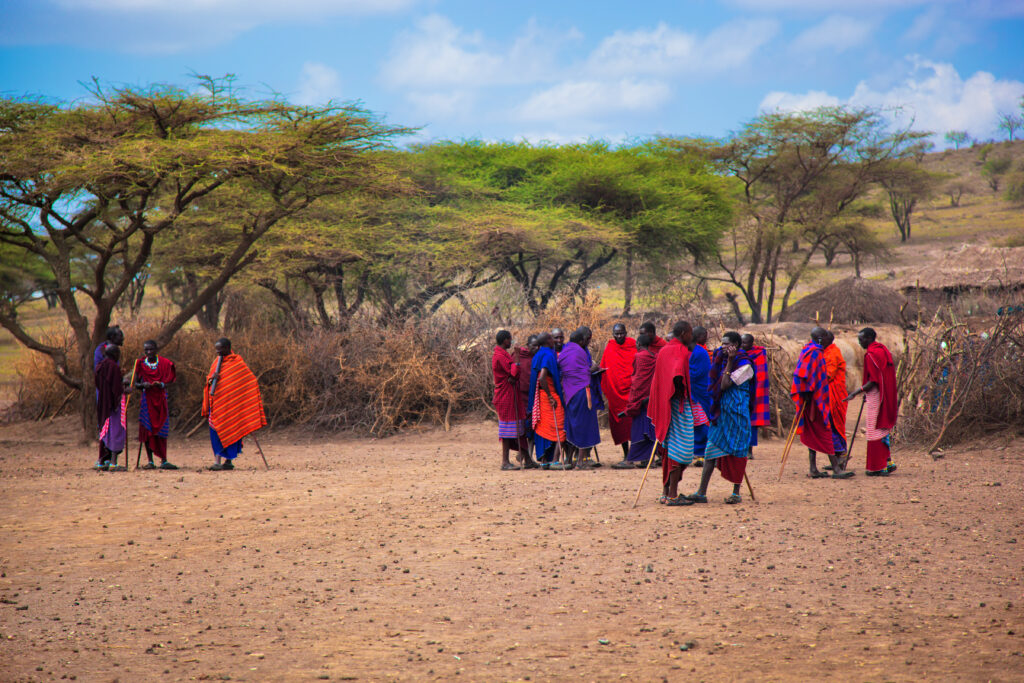 Maasai village, TANZANIA, AFRICA : A group of Maasai people in traditional clothes in front of their village on December 11, 2012 in Tanzania. Maasai people are among the best known of African ethnic groups, due to their residence near the many game parks of East Africa, and their distinctive customs and dress